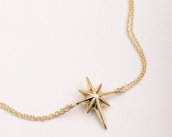 May include: A gold necklace with a star-shaped pendant. The pendant is a stylized, pointed star with a three-dimensional design.