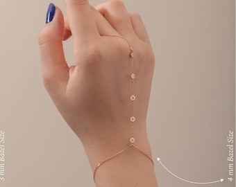 May include: Two gold chain bracelets with small round stones set in bezels. The bracelet on the left has 3 mm bezels and the bracelet on the right has 4 mm bezels. The bracelets are shown on a model's hand.