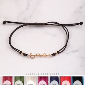 May include: A black macrame cord bracelet with a gold medical symbol charm. The bracelet is adjustable and comes in a variety of colors, including burgundy, green, cream, purple, blue, red, and black.