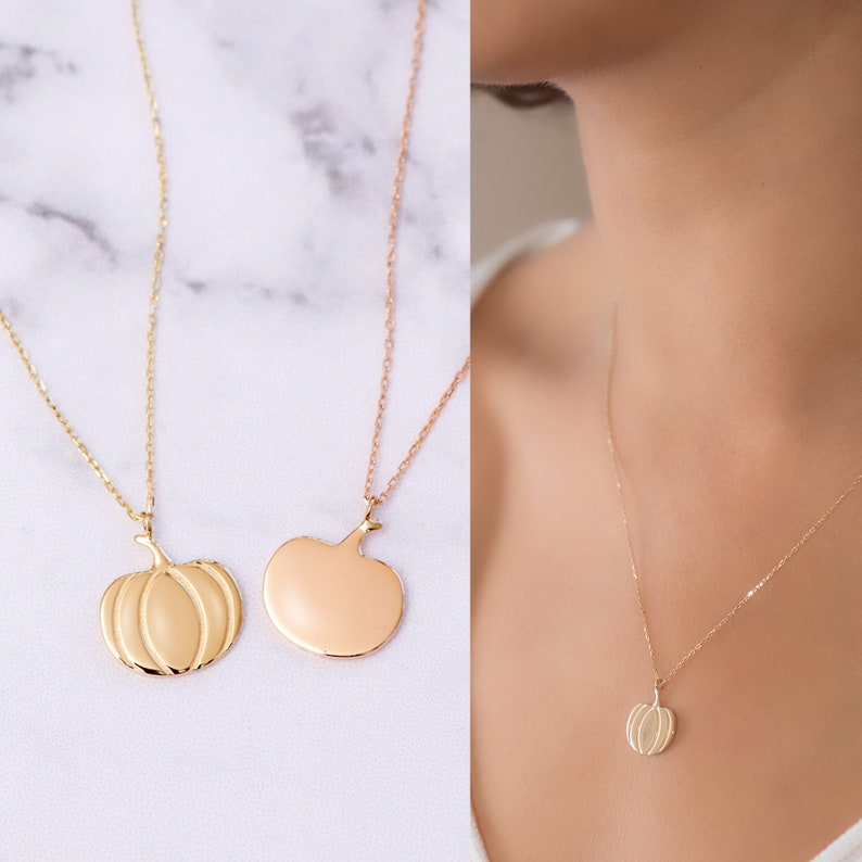 Puede incluir: Dos collares de oro con colgantes de calabaza. Un collar tiene un colgante de calabaza detallado, mientras que el otro tiene un colgante de calabaza liso y s&oacute;lido.