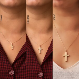 May include: Three gold cross necklaces on models, showing the different sizes: small, medium, and large. The necklaces are on a plain background.