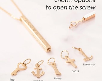 May include: A gold-colored necklace with a rectangular pendant engraved with a name, date, and phrase. The image also shows various small gold charms, including a key, anchor, bone, cross, and hammer. Text on the image reads "charm options to open the screw."