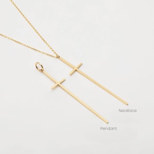 May include: A gold necklace with a long, thin cross pendant. The pendant is attached to a delicate chain. The necklace is labeled "Necklace" and the pendant is labeled "Pendant".
