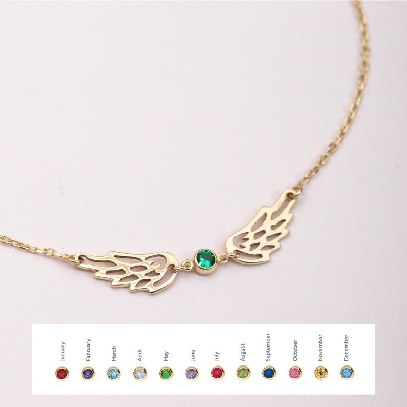 Puede incluir: Un collar dorado con alas caladas y una gema verde central. El delicado collar de cadena incluye una selecci&oacute;n de gemas de colores que representan los meses de nacimiento.