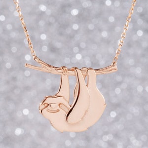 Pode incluir: Um colar de ouro rosa com um pingente de pregui&ccedil;a pendurado em um galho. A pregui&ccedil;a &eacute; feita de metal e tem um design detalhado.