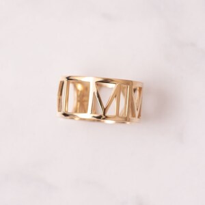 Pode incluir: Um anel dourado com um design de algarismos romanos. O anel &eacute; feito de metal e tem um design simples e elegante.