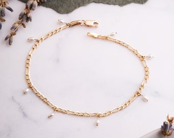 May include: A gold chain bracelet with small white pearls dangling from it.