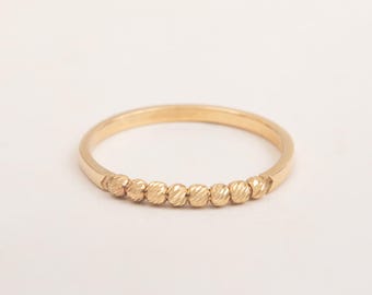 May include: A thin gold band ring with a row of textured beads along the top.