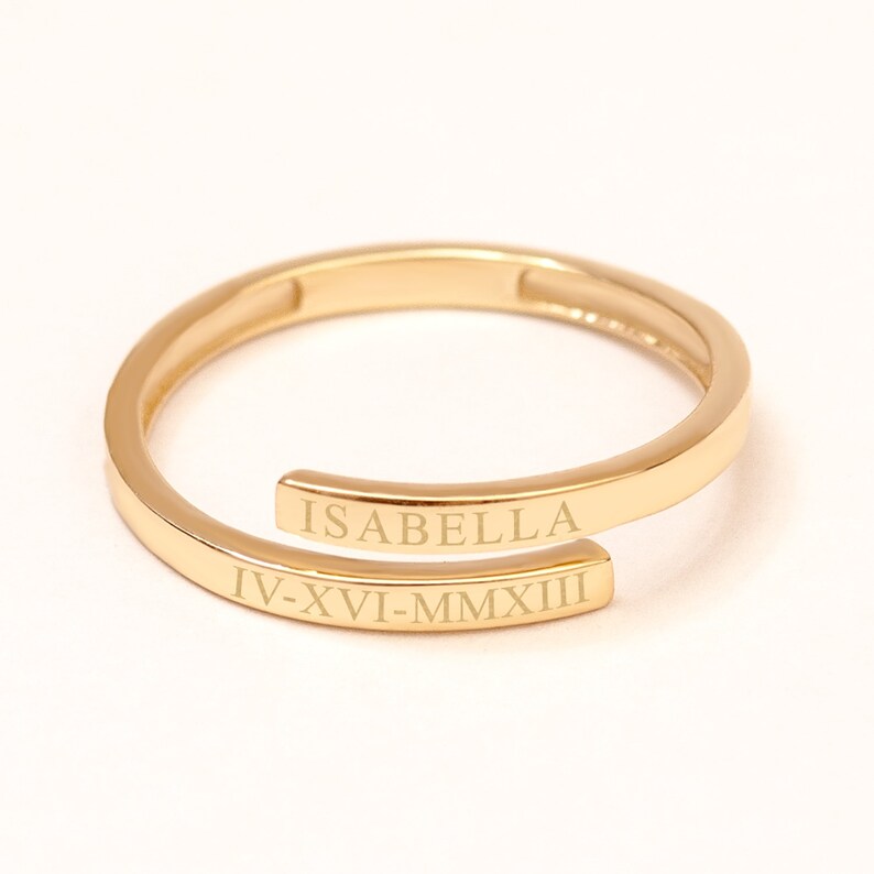 Classic script custom gold name ring with engraved text and date, minimalist wrap band design.