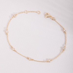 Op de afbeelding: Een fijne gouden kettingarmband met zes gelijkmatig verdeelde, in een zetting geplaatste ronde, heldere stenen. De armband is voorzien van een ronde veerringsluiting en twee kleine verstelringen aan het uiteinde van de ketting.