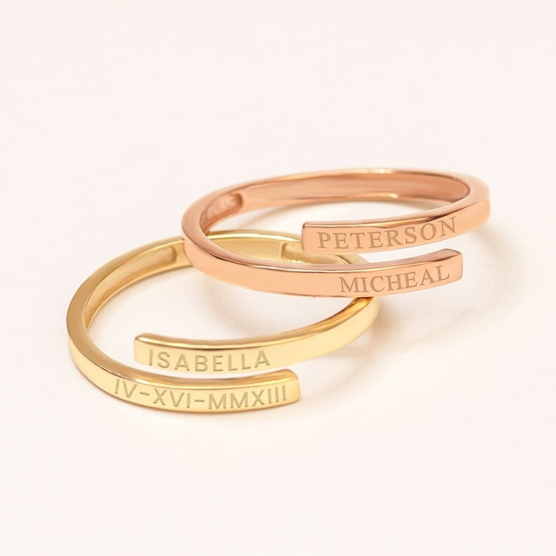 Personalized real gold name rings in classic wrap style, featuring engraved names in rose and yellow gold bands.