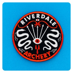 May include: A black and red embroidered patch with the words "Riverdale Archery" and a stylized eye with snakes and arrows around it.