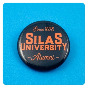 Puede incluir: Botón negro y naranja con el texto "Since 1698 Silas University - Alumni -"