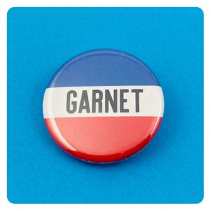 May include: A red, white, and blue button with the word "GARNET" printed in black.