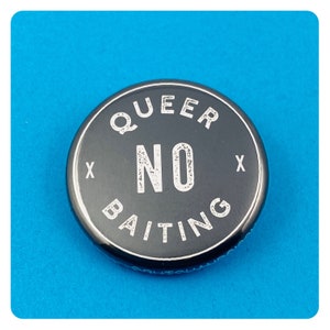 May include: A black button with white text that reads "QUEER NO BAITING" with an "X" on either side of the word "NO".