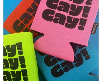 May include: Four colourful can coolers with the word "gay" printed in black on each. The coolers are in the colours red, pink, blue, and green.
