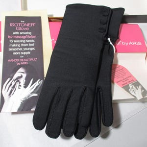 Pode incluir: Luvas Isotoner pretas com tr&ecirc;s pequenos bot&otilde;es no punho, expostas na caixa original. A caixa inclui um encarte promocional com texto sobre as luvas e a frase "Hands Beautiful".