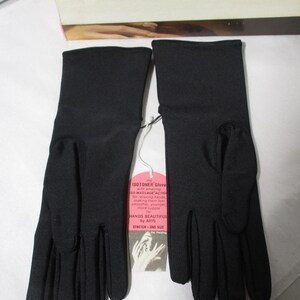 Pode incluir: Um par de luvas pretas Isotoner com uma etiqueta anexada. A etiqueta diz "SO-MASSAGE ACTION" e "HANDS BEAUTIFUL by ARIS". As luvas s&atilde;o el&aacute;sticas, tamanho &uacute;nico.
