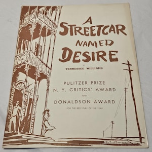 May include: A vintage book cover for the play "A Streetcar Named Desire" by Tennessee Williams. The cover features brown illustrations of a building and figures, with the title in large, stylized letters. Awards are listed below.