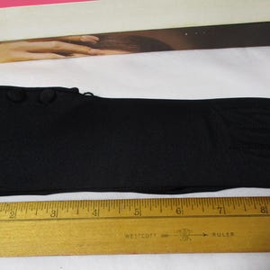 Pode incluir: Uma luva preta com tr&ecirc;s bot&otilde;es decorativos no pulso. A luva tem aproximadamente 25 cm de comprimento. Uma r&eacute;gua de madeira &eacute; colocada ao lado da luva para medi&ccedil;&atilde;o.