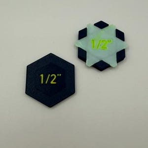 May include: Two hexagonal markers with the text 1/2" printed on them. One marker is solid black with yellow text, while the other features a black hexagonal base topped with a light green star-shaped overlay displaying the text 1/2" in yellow.