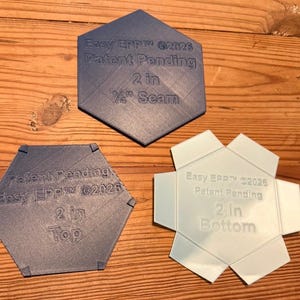 May include: Three hexagonal quilting templates labeled Easy EPP 2026 Patent Pending. One dark blue hexagon is marked 2 in 1/4 in Seam. A second dark blue hexagon is marked 2 in Top. A light blue hexagon with six extended tabs is marked 2 in Bottom.
