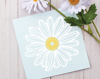 May include: A white sticker with a blue background featuring a white daisy with a yellow center. The daisy is outlined in white.
