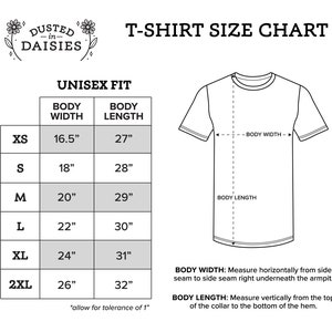 May include: A white T-shirt size chart with measurements in inches. The chart includes sizes XS to 2XL, with body widths from 16.5" to 26" and body lengths from 27" to 32". The text "Dusted in Daisies" is at the top.