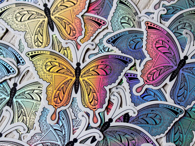 May include: A collection of colorful butterfly stickers with intricate patterns. The stickers feature a gradient of colors, including yellow, orange, pink, purple, and blue. The butterfly designs have detailed wing patterns and black antennae.