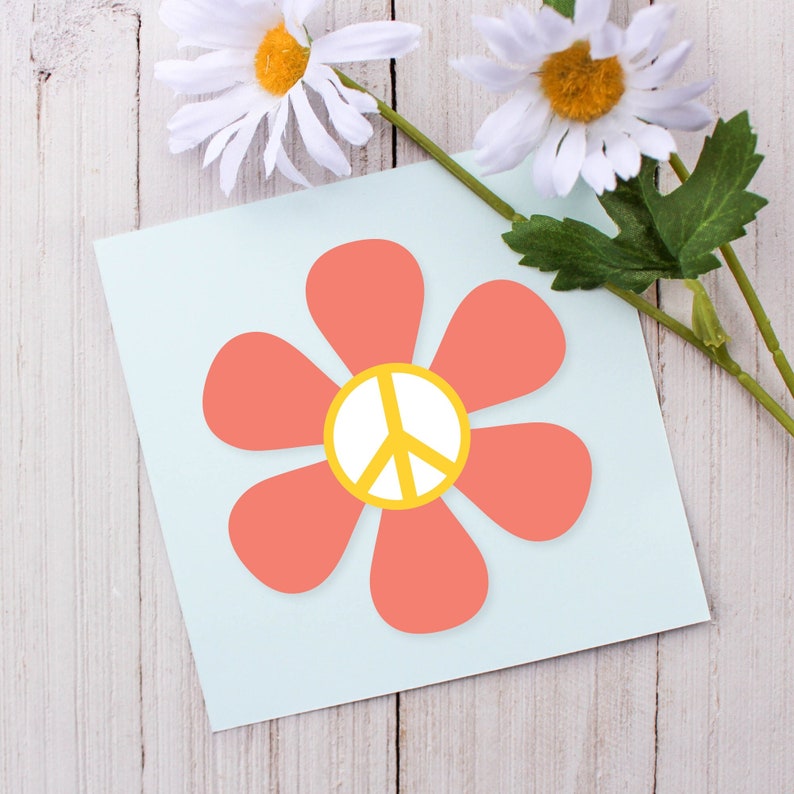 May include: A light blue card with a pink flower with a yellow peace sign in the center. The flower has six petals.