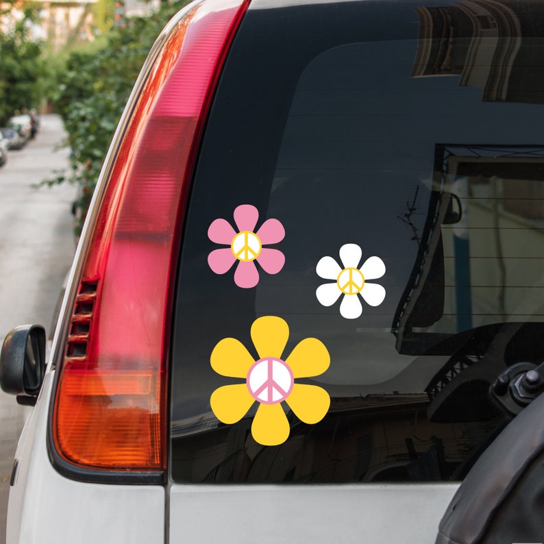May include: Three peace sign stickers in the shape of flowers. The flowers are yellow, pink, and white. The peace signs are white.