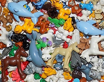 May include: A collection of colorful plastic animal figurines, including a dolphin, a tiger, a horse, and a variety of other animals. The figurines are made of a smooth, glossy plastic and are in various colors, including blue, yellow, brown, and white.