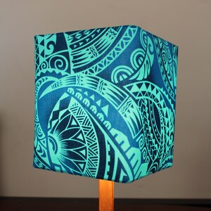 May include: A teal and black patterned lampshade with a wooden base. The lampshade features a geometric design.