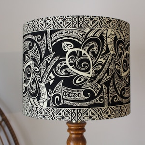 May include: Black and white lampshade with a Polynesian tribal design. The design features intricate patterns and swirls.