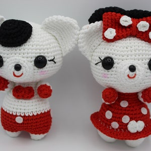May include: Two white crocheted stuffed animals with red and white polka dot dresses. One animal has a black bow and the other has a black hat.