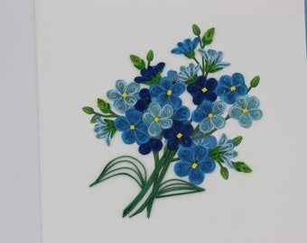 Könnte beinhalten: Ein handgemachter Papierblumenstrauß mit blauen und hellblauen Blüten und grünen Blättern. Die Blüten sind aus gekräuseltem Papier gefertigt und haben gelbe Zentren.