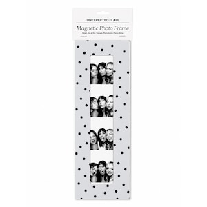 May include: A white magnetic photo frame with black polka dots, featuring a vertical cutout for a 2 inch by 6 inch vintage photobooth photo strip. The packaging header reads Unexpected Flair Magnetic Photo Frame Fits 2in x 6in Vintage Photobooth Photo Strip.