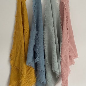 May include: Four fabric squares with frayed edges in different colours: mustard yellow, light blue, sage green, and pale pink.