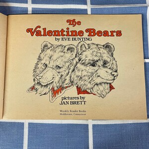 May include: The Valentine Bears book cover features two brown bears with red and white scarves. The book is by Eve Bunting and illustrated by Jan Brett. The book is published by Weekly Reader Books in Middletown, Connecticut.