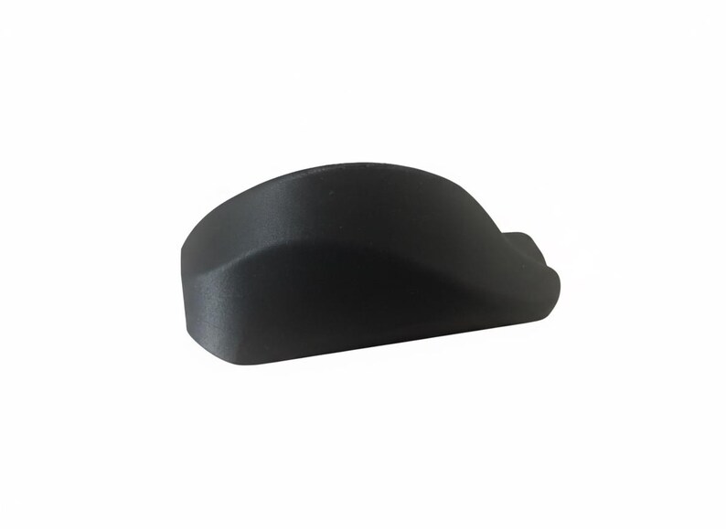 Pode incluir: Um objeto preto s&oacute;lido, curvo, com um acabamento liso e fosco. A forma lembra um design ergon&ocirc;mico pequeno, possivelmente um componente ou acess&oacute;rio. O objeto est&aacute; sobre um fundo branco liso.