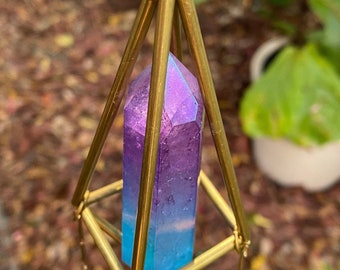 May include: A gold metal wind chime with a purple and blue crystal prism hanging in the centre. The chime has five clear crystal drops hanging from the bottom.