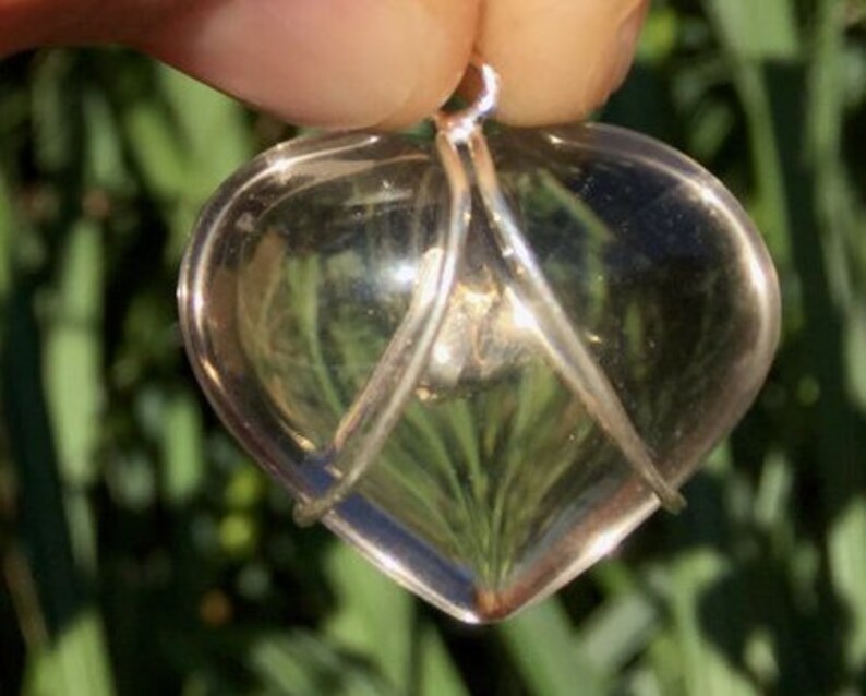 Pu&ograve; includere: Un ciondolo a forma di cuore in quarzo trasparente avvolto in filo d'argento. Il ciondolo &egrave; a forma di cuore e ha un'anellina in argento per appenderlo.