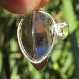 Pu&ograve; includere: Un ciondolo d'argento con un cristallo di quarzo trasparente e una piccola pietra preziosa verde. Il ciondolo ha la forma di una lacrima e ha un'anellina in argento.