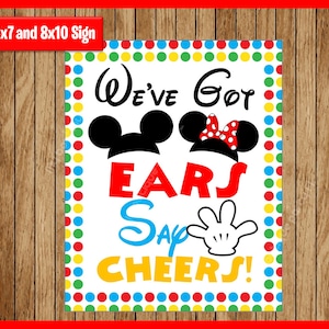 May include: A white sign with a colorful polka dot border. The sign says "We've Got Ears Say Cheers!" with Mickey Mouse and Minnie Mouse ears on either side of the text. The sign is 5x7 and 8x10 inches.