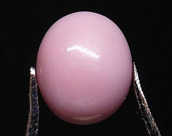 May include: A single, round, pink pearl held by tweezers against a black background.