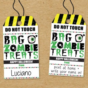 May include: Two printable Halloween treat bag tags with a black and yellow striped warning sign design. The text reads "Do Not Touch Bag O' Zombie Treats" with a green eye graphic. One tag has the text "Happy Halloween! From" and a blank space for a name. The other tag has the text "Happy Halloween! From print at home + write your name in!"