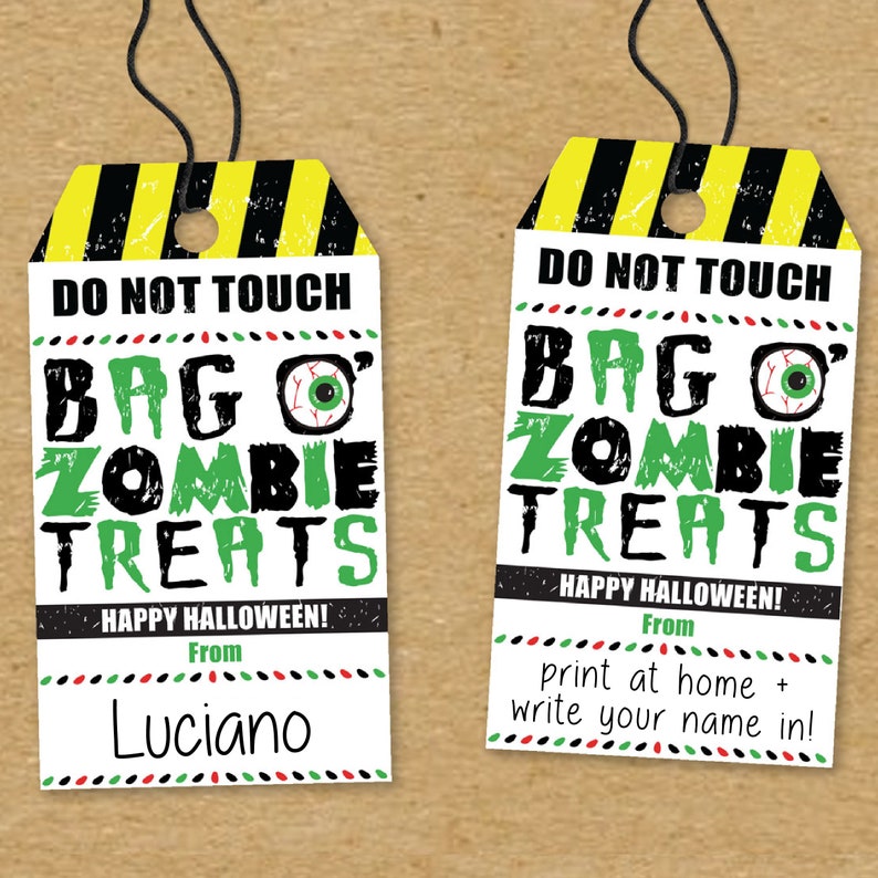 May include: Two printable Halloween treat bag tags with a black and yellow striped warning sign design. The text reads "Do Not Touch Bag O' Zombie Treats" with a green eye graphic. One tag has the text "Happy Halloween! From" and a blank space for a name. The other tag has the text "Happy Halloween! From print at home + write your name in!"