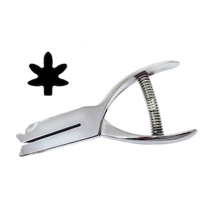May include: A silver metal punch tool with a spring mechanism. The punch creates a leaf-shaped hole in paper or cardstock.