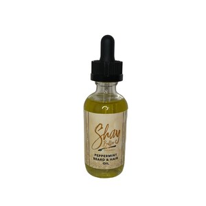 May include: A glass bottle of Shay Butter Organics Peppermint Beard & Hair Oil. The bottle is clear and has a brown label with the company name and product name.