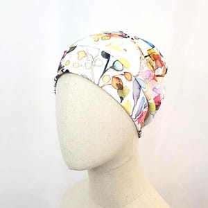 Puede incluir: Gorro blanco con estampado floral en tonos rosa, amarillo y azul.